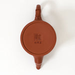 Red ceramic teapot lid with a logo on a white background