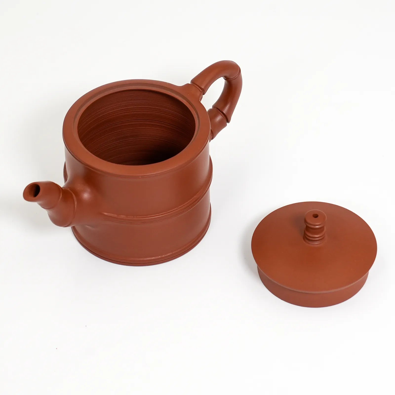 Red clay teapot with lid on a white background