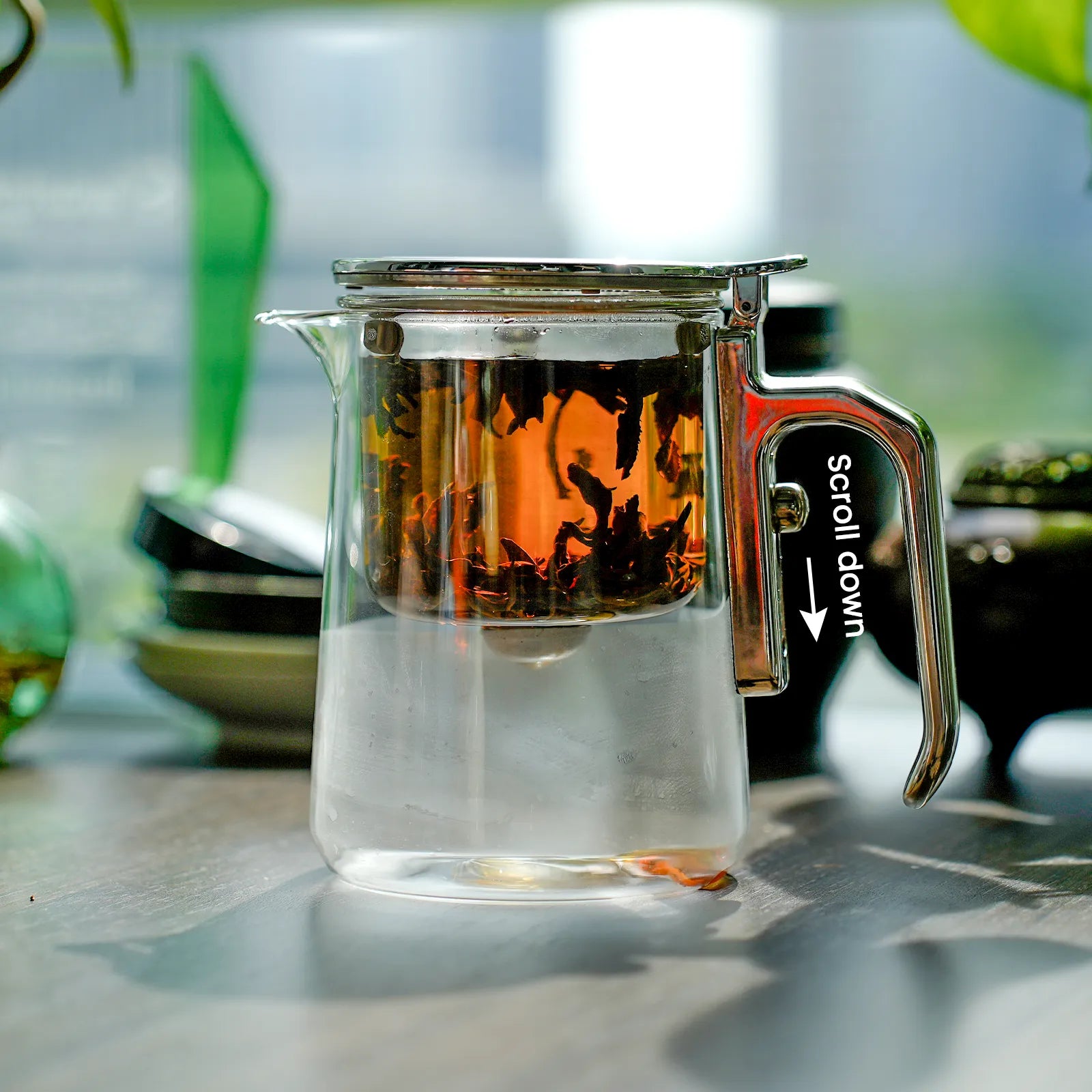 Clear glass teapot with a metal handle on a blurred background
