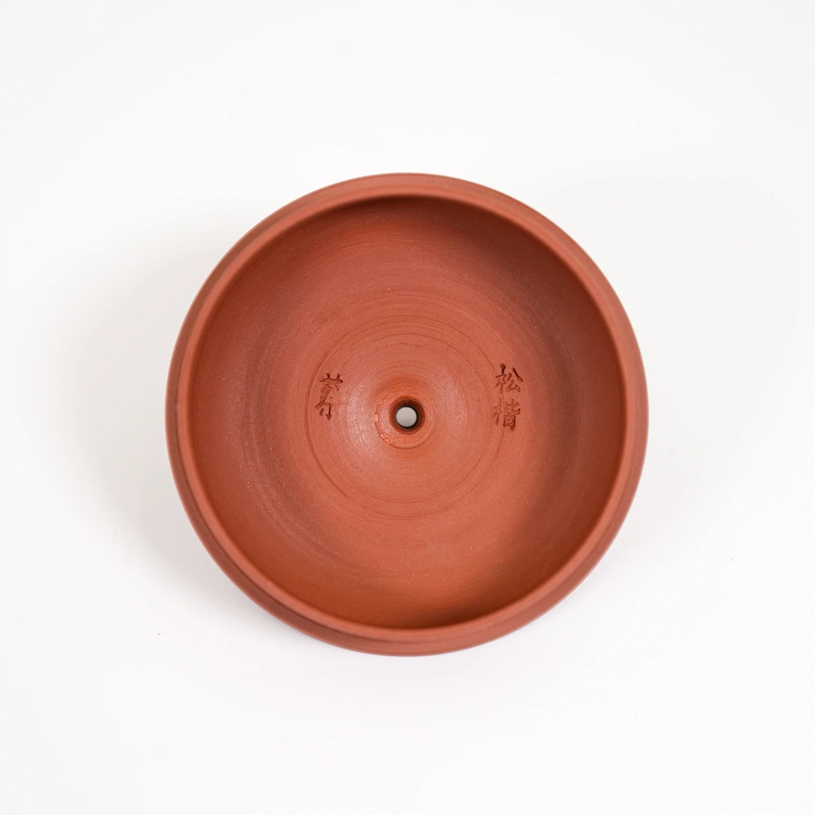 Terracotta pot with engraved text on a white background