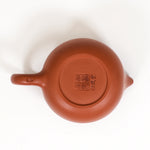 Red ceramic teapot with a logo on a white background