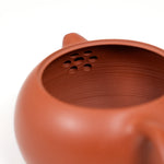 Close-up of a terracotta teapot with a textured interior on a white background