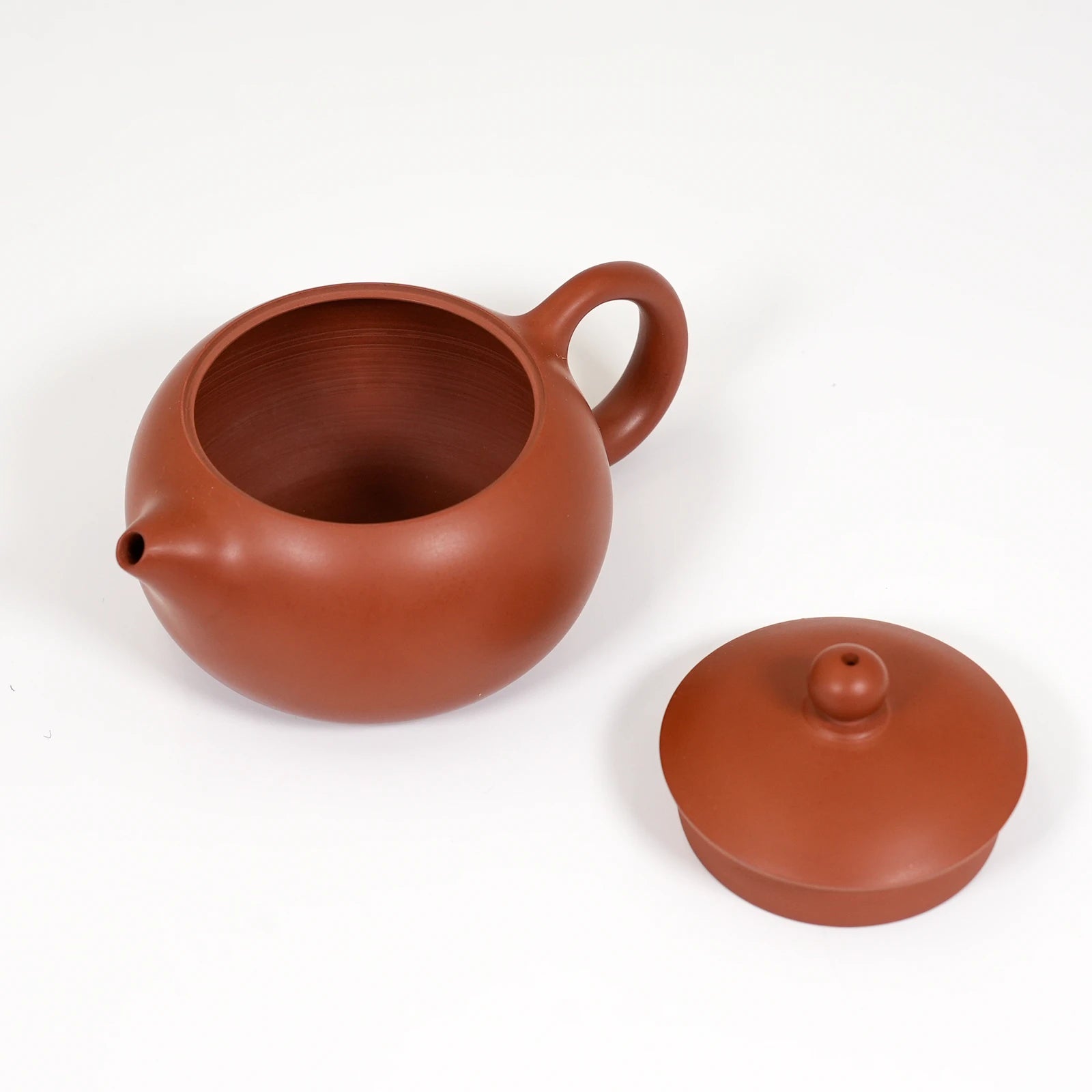 Red clay teapot with lid on a white background