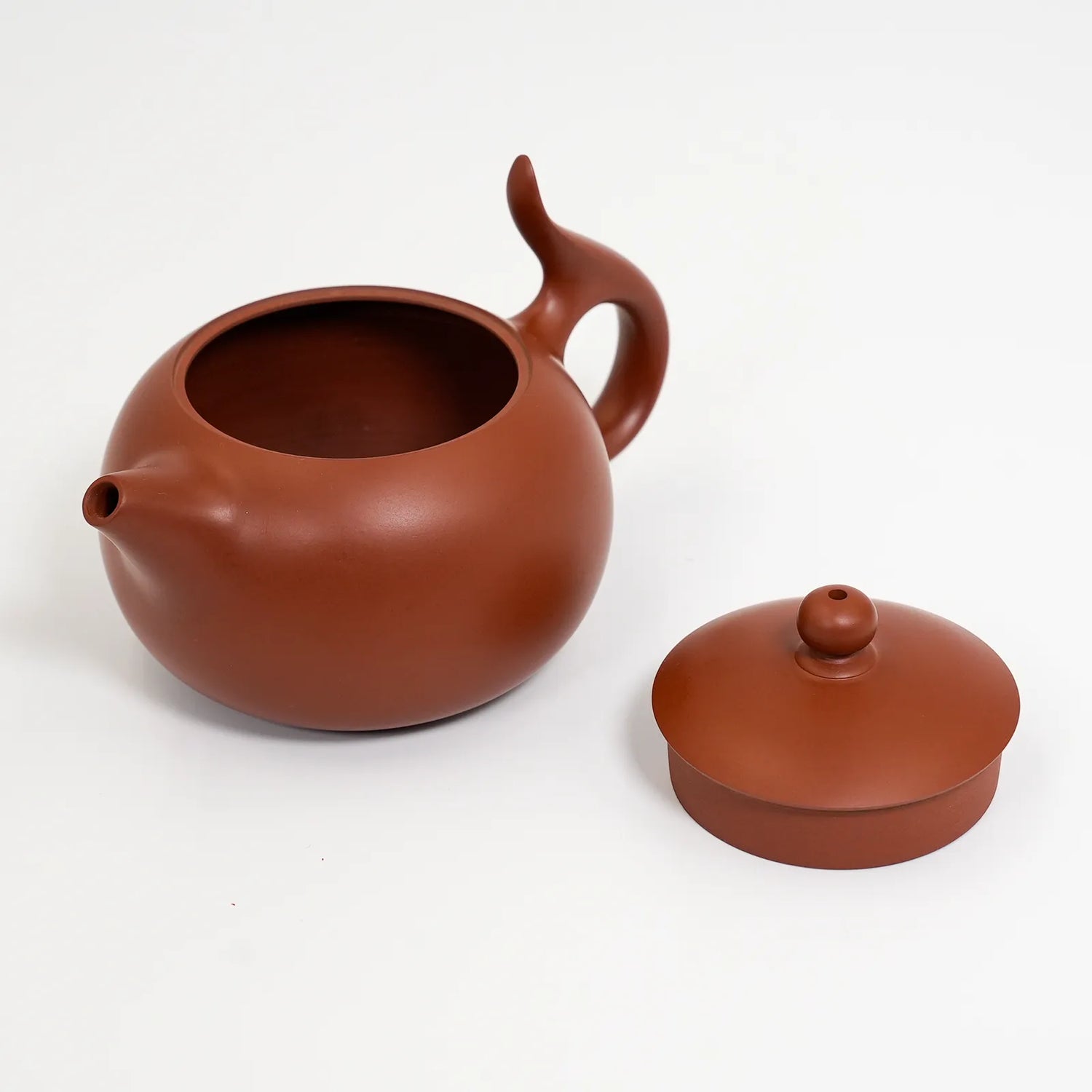 Red clay teapot with lid on a white background